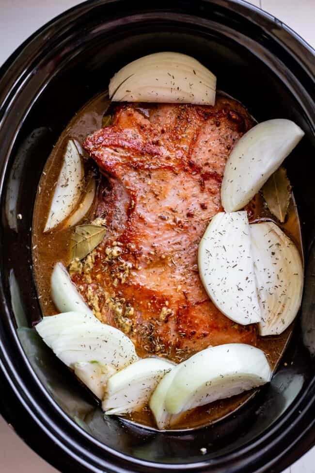 seared corned beef and onions in a crock pot.