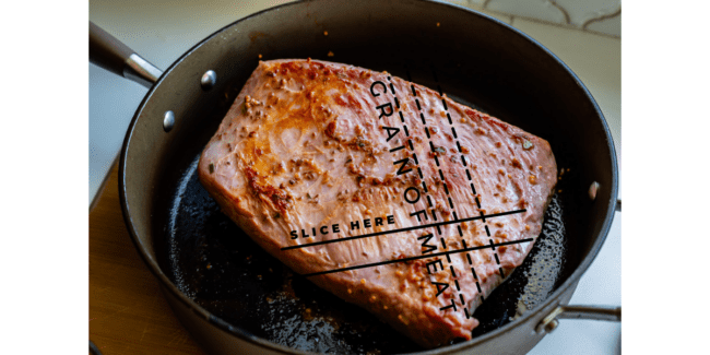 corned beef searing in a pan with diagrams of how to slice against the grain.