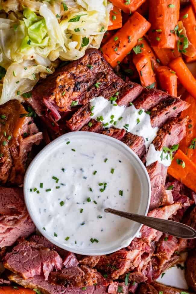 creamy horseradish sauce in a bowl with corned beef and cabbage around it.