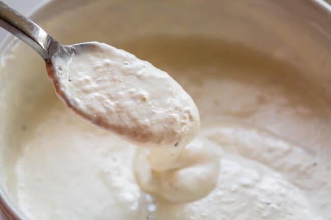 horseradish sauce being lifted from a bowl with a spoon.