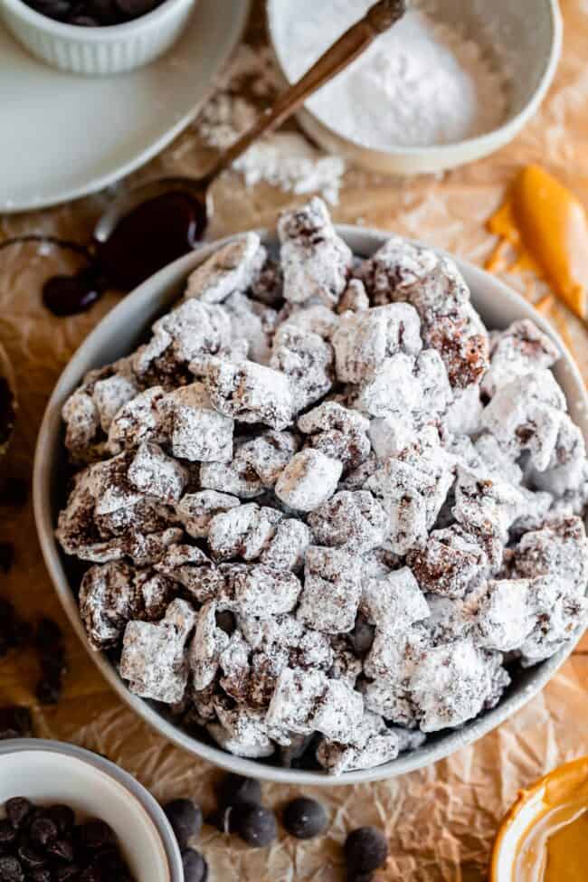 a large bowl of puppy chow recipe chex garnished with melted chocolate and peanut butter