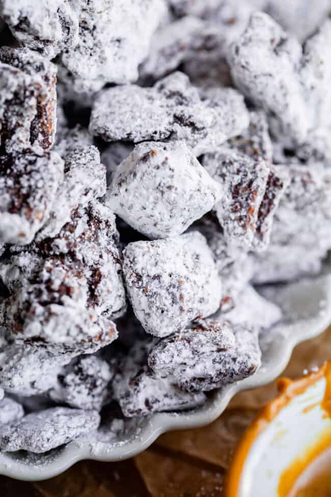 puppy chow recipe Chex with chocolate and covered in powdered sugar on a plate.
