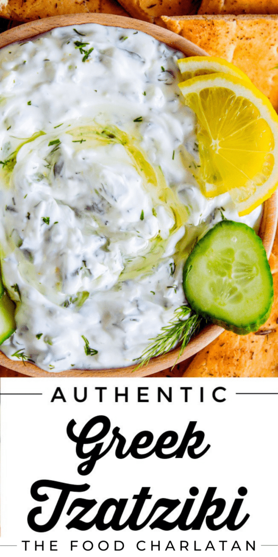 Greek tzatziki sauce in a wooden bowl with lemons and cucumbers.