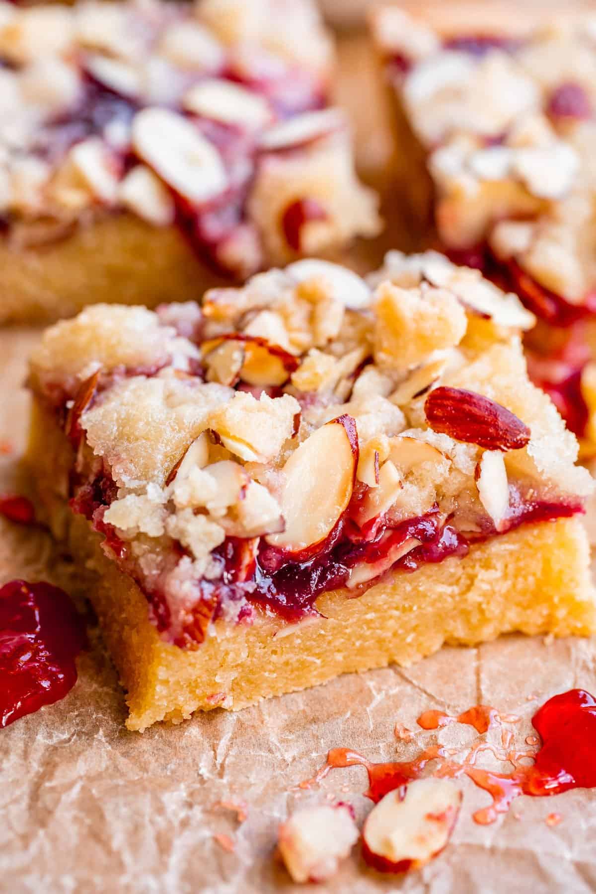 picture of raspberry shortbread bars shot from the side with jam and almond streusel.