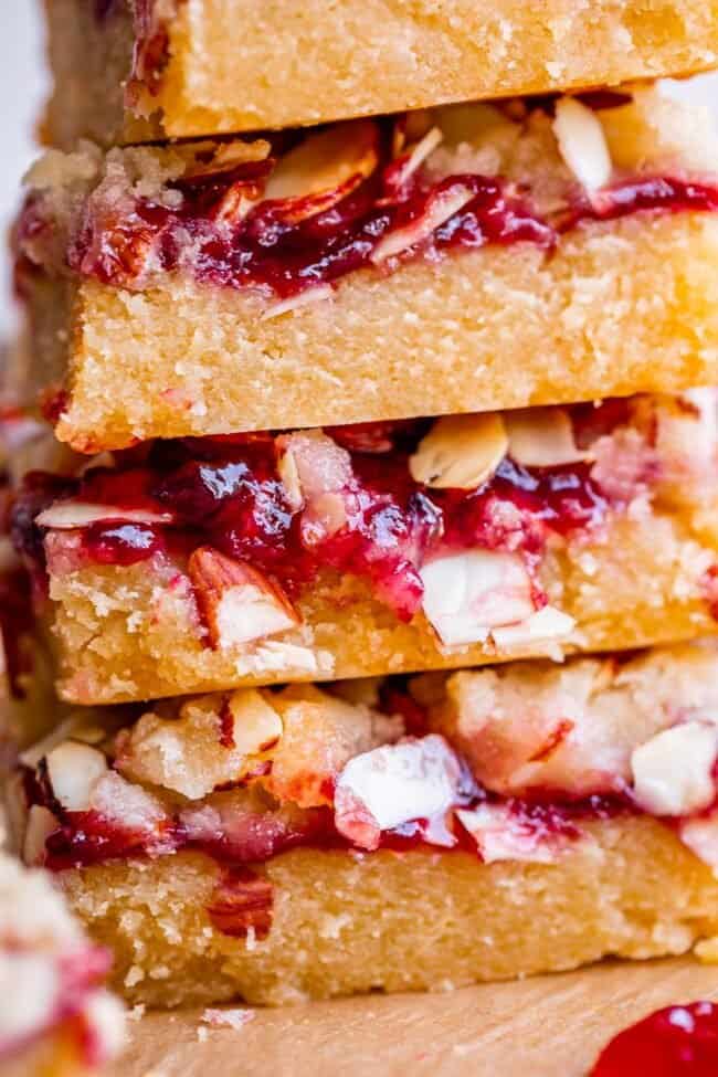 raspberry crumb bars in a stack topped with almonds and jam.