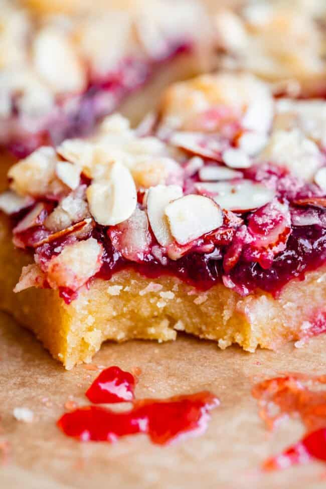 raspberry crumble bar on parchment paper with a bite taken out.