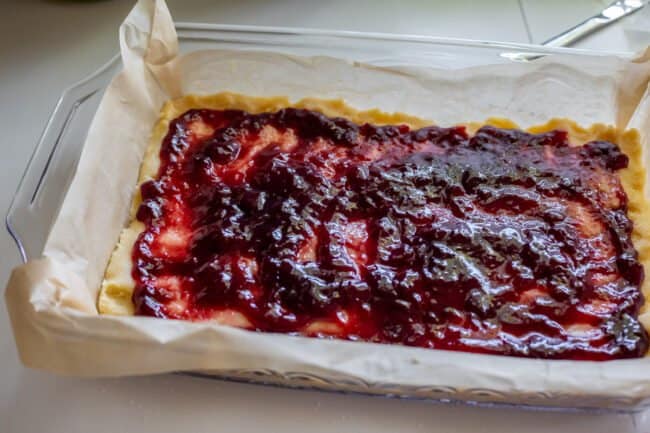 shortbread crust pressed into a parchment lined glass pan topped with jam.