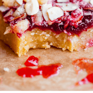 a bite taken out of raspberry crumb bar with almond topping.