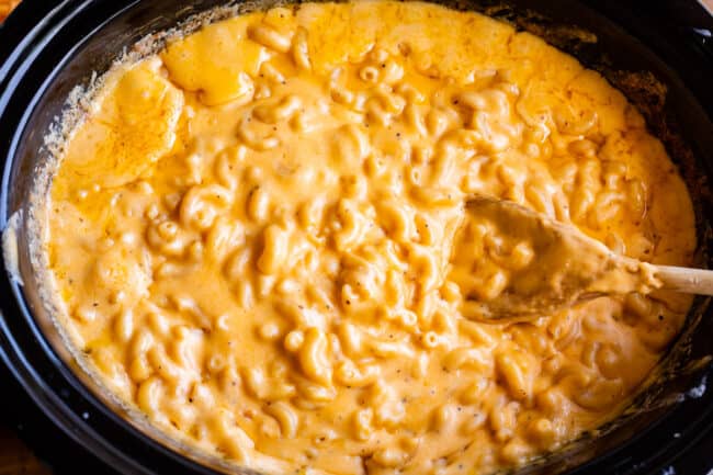 best slow cooker mac and cheese in the pot with wooden spoon, shot overhead.