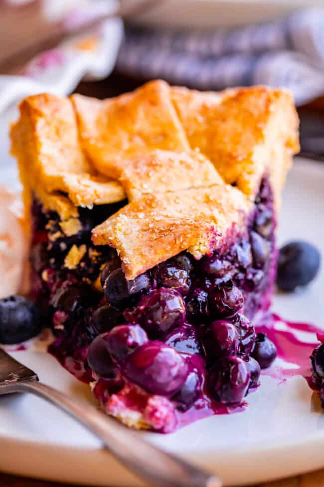 slice of best blueberry pie recipe from the front, on a plate with fork.