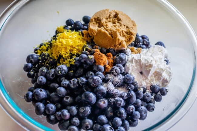 glass bowl full of blueberry pie filling ingredients.