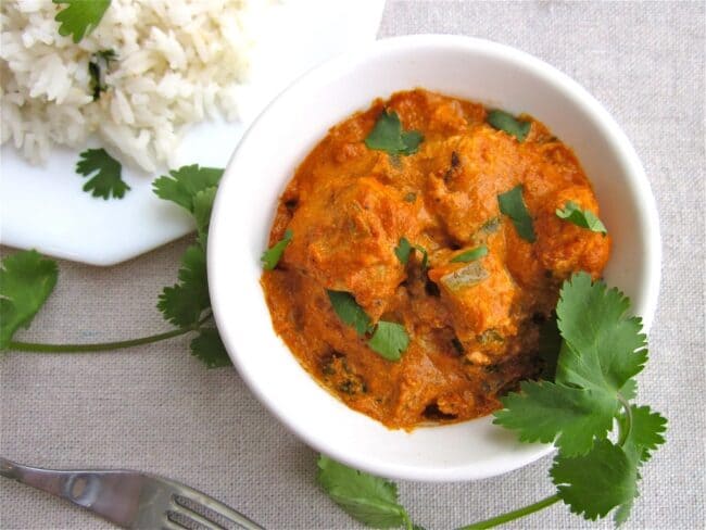 Chicken tikka masala in white bowl with cilantro garnish.