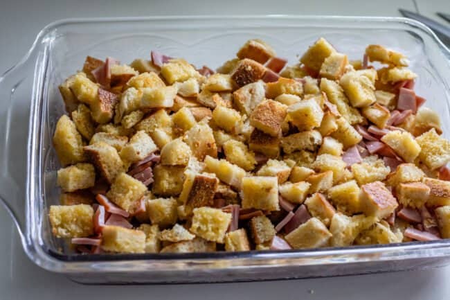 English muffins and canadian bacon chopped in a casserole dish.