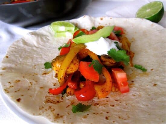 Vegetarian chickpea fajitas on flour tortilla with sour cream and guacamole.