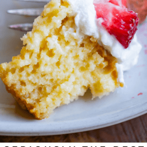 A forkful of tres leches cake topped with whipped cream and sliced strawberries sits on a white plate. Text below reads, Seriously delicious tres leches cake. The Food Charlatan.