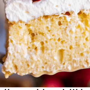 A close-up of a slice of tres leches cake topped with whipped cream and fresh strawberries, highlighting its moist, airy texture. Text below reads the most irresistible Tres Leches Cake - The Food Charlatan, a classic dessert delight.