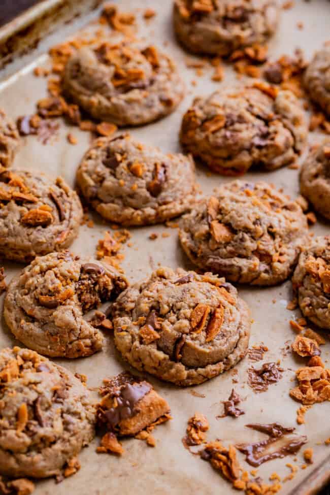 butterfinger cookie recipe with all the cookies lined up on a parchment lined baking sheet, with extra crushed butterfinger.