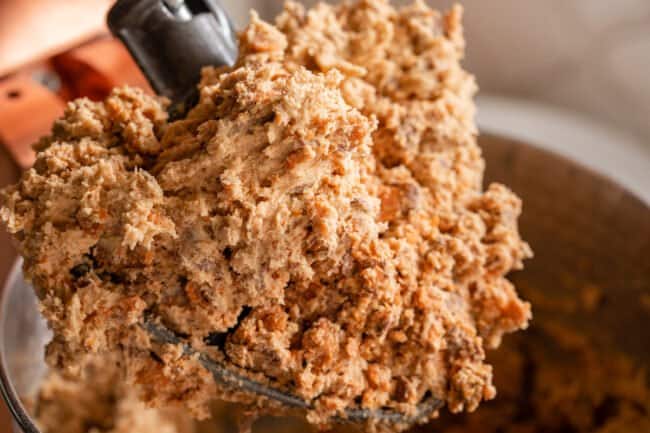 peanut butter butterfinger cookie dough on the paddle of a stand mixer.