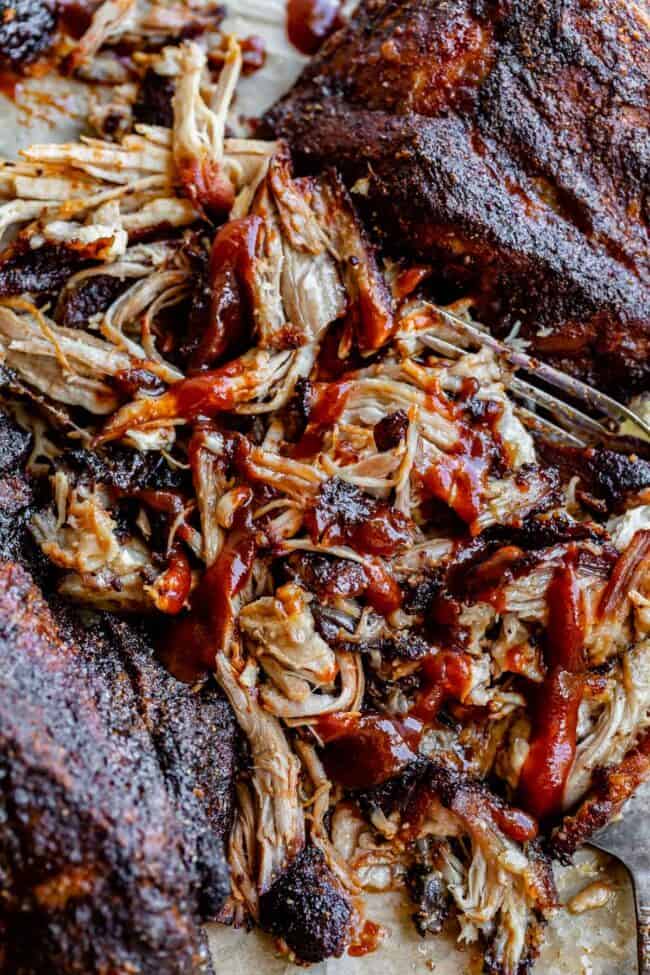 pulled pork made in the oven shredded on parchment paper with bbq sauce.