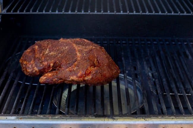 raw pork shoulder rubbed with spices placed on a grill.