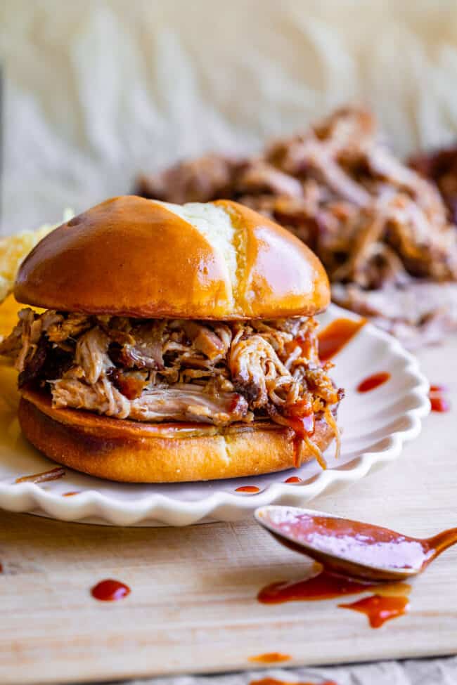 pulled pork sandwich on a white plate with barbecue sauce.