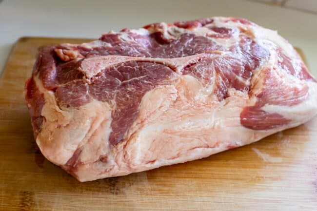 pork shoulder with fat cap on a wooden cutting board.