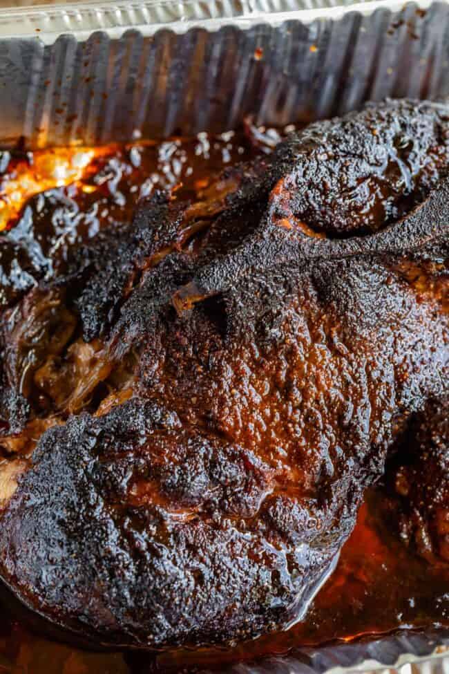 smoked pulled pork with blackened bark crust in a aluminum pan.