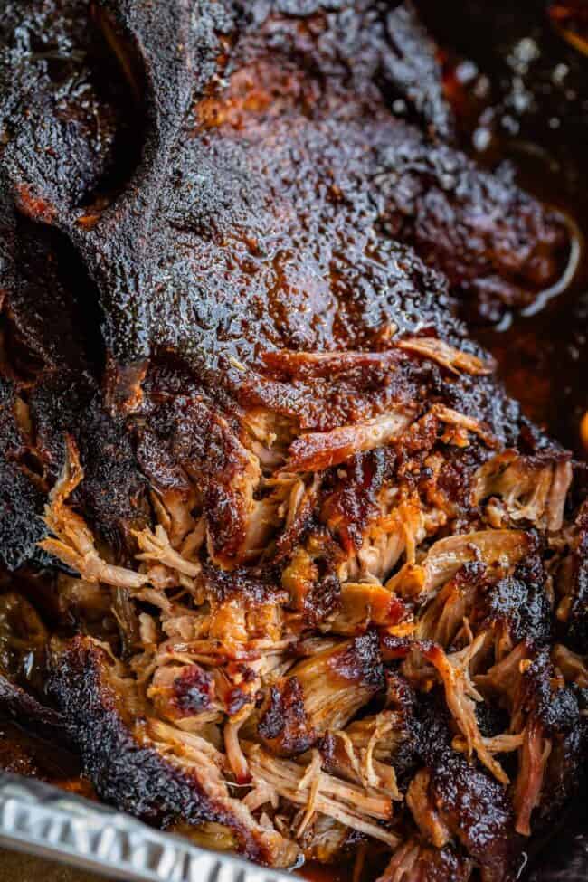 partially shredded smoked pulled pork shoulder made on a gas grill, in an aluminum pan.