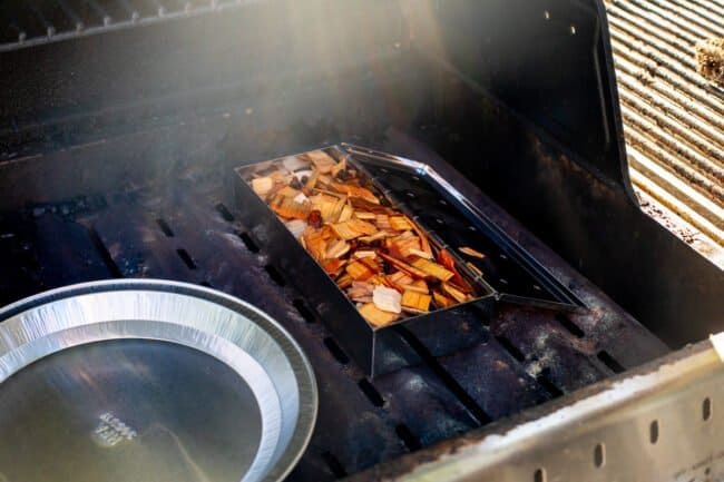 wood chips in a smoker box set on the heat plates of a grill.