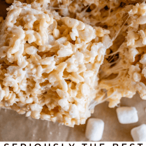 Close-up of gooey Rice Krispie treats stacked together, with soft marshmallow pieces visible. Text at the bottom reads “Seriously the Best Rice Krispie Treats – The Food Charlatan.” Perfect marshmallow flavor in every bite!.