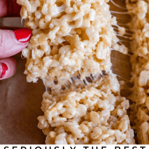 A hand pulls a gooey, marshmallow-filled Rice Krispie treat from a pan. Text at the bottom reads, Seriously irresistible Rice Krispie Treats. The Food Charlatan.
