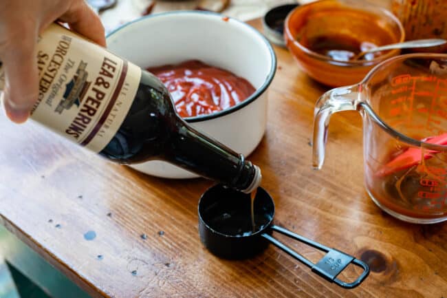 pouring worcestershire sauce into a 1/3 measuring cup on a table.