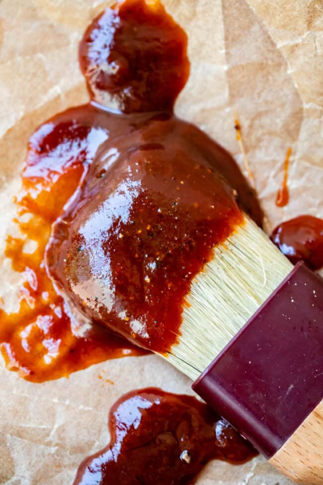 close up of easy bbq sauce on a white brush on parchment paper.