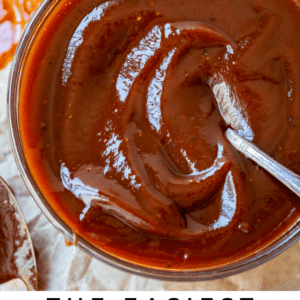 bowl of bbq sauce with a spoon on parchment paper.