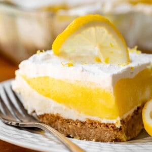 Slice of lemon lush on white plate with silver fork.