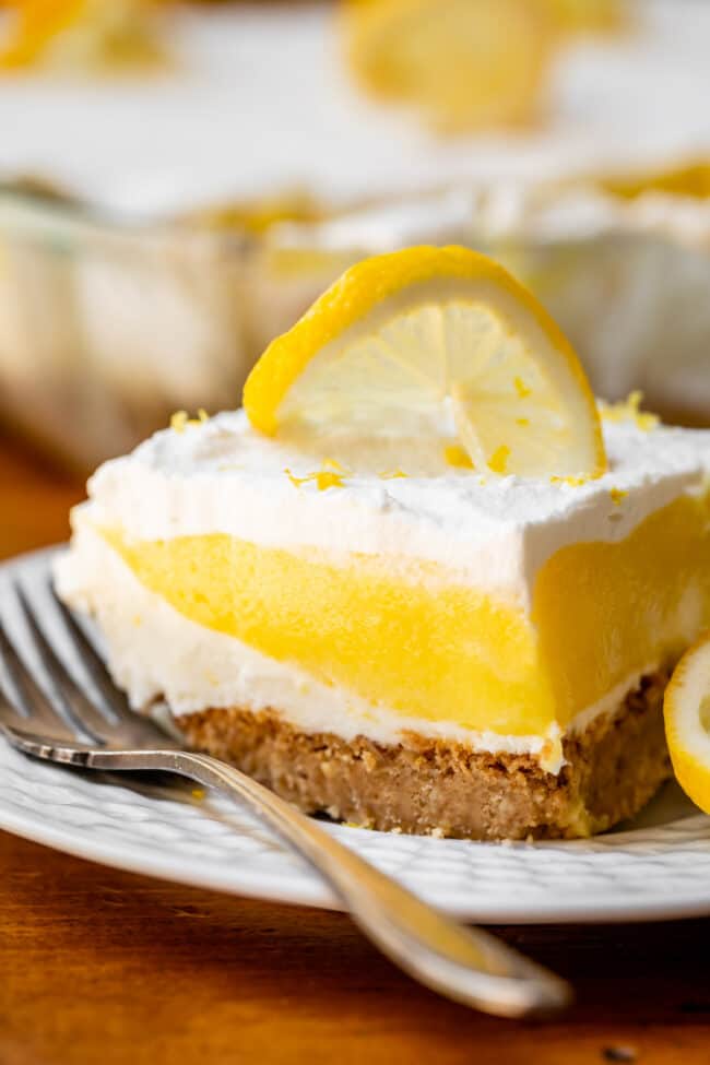 Slice of lemon lush on white plate with silver fork.