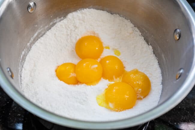 Several egg yolks in dry pudding mix in a pot.