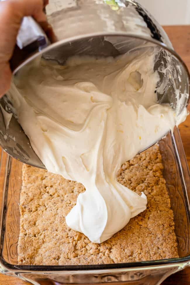 Pouring cream cheese filling onto cookie crust in 9x13 dish.