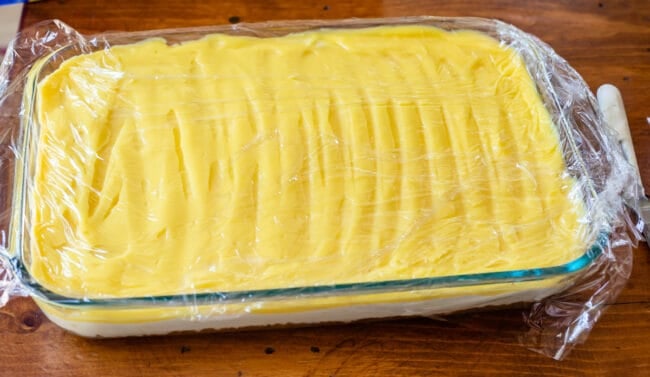 Plastic wrap over prepared lemon dessert.