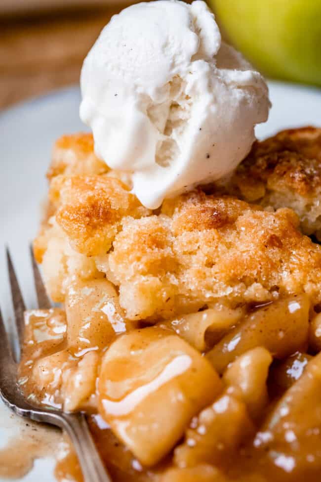 Apple cobbler recipe on a white plate with fork, topped with ice cream.