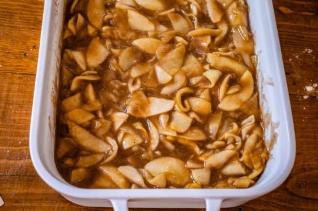 cooked apples in sauce in a white casserole dish.