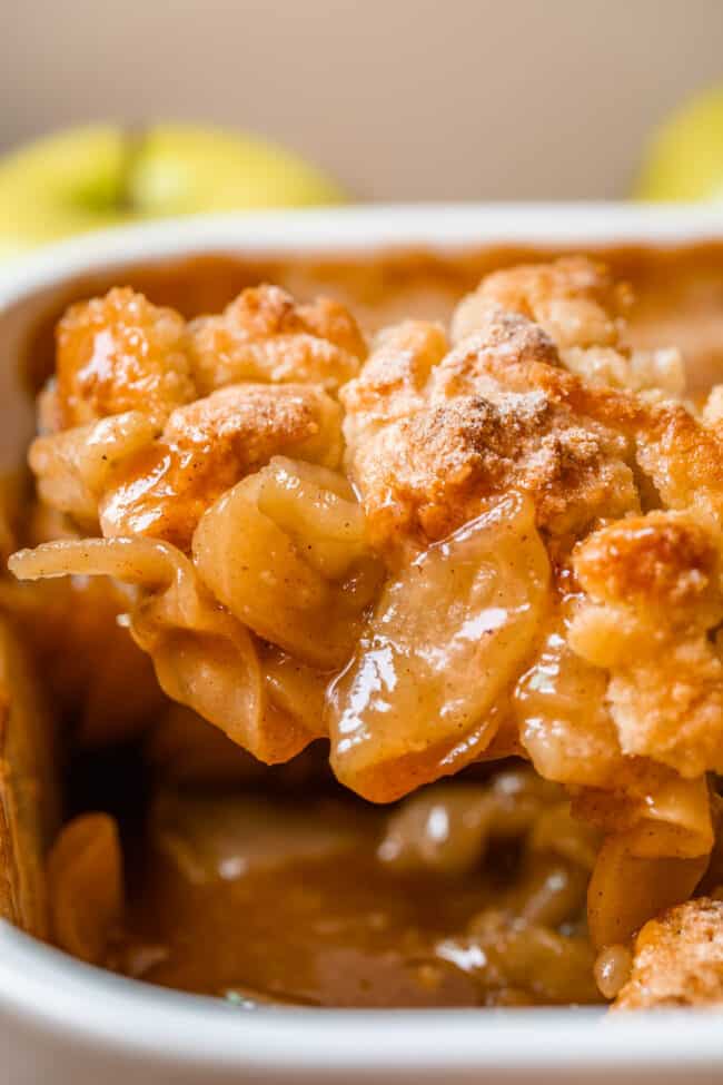 apple cobbler being lifted from a casserole dish with a spoon.