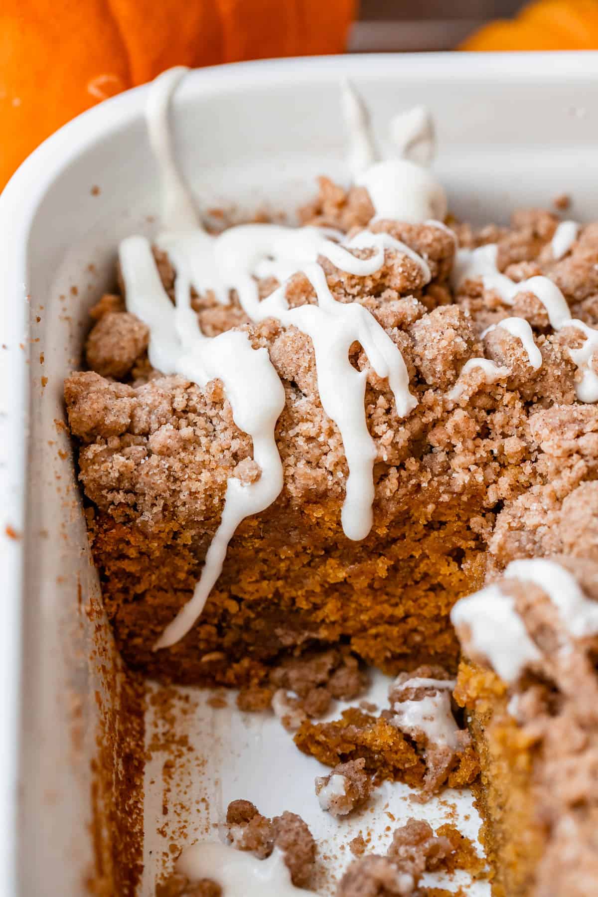 pumpkin coffee cake in a white casserole dish, topped with glaze.