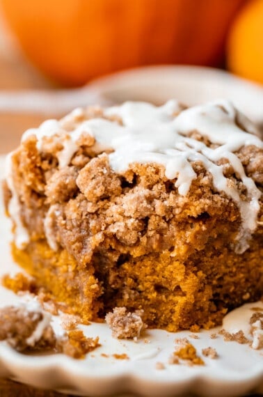 pumpkin spice coffee cake with drizzled glaze on a white plate.