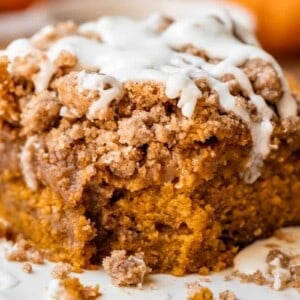 a bite taken out of a piece of pumpkin coffee cake on a plate.