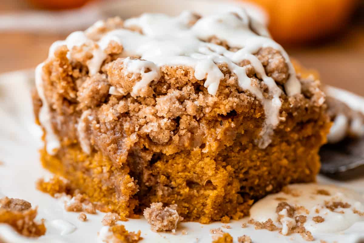 a bite taken out of a piece of pumpkin coffee cake on a plate.