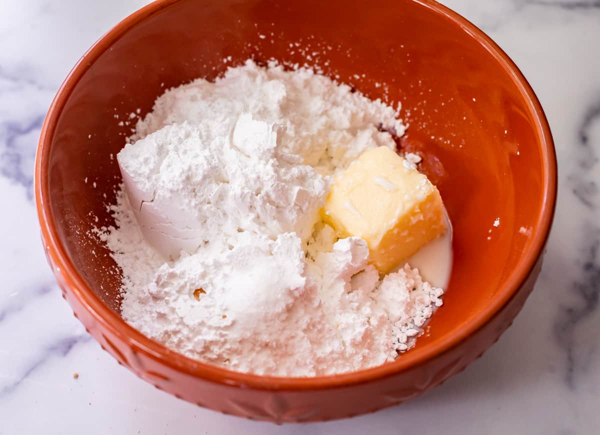 powdered sugar, butter, and milk in a bowl ready to be mixed.