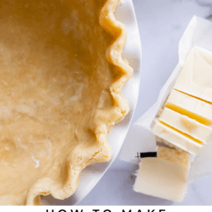 flaky homemade pie crust in a pie pan with butter and flour nearby.
