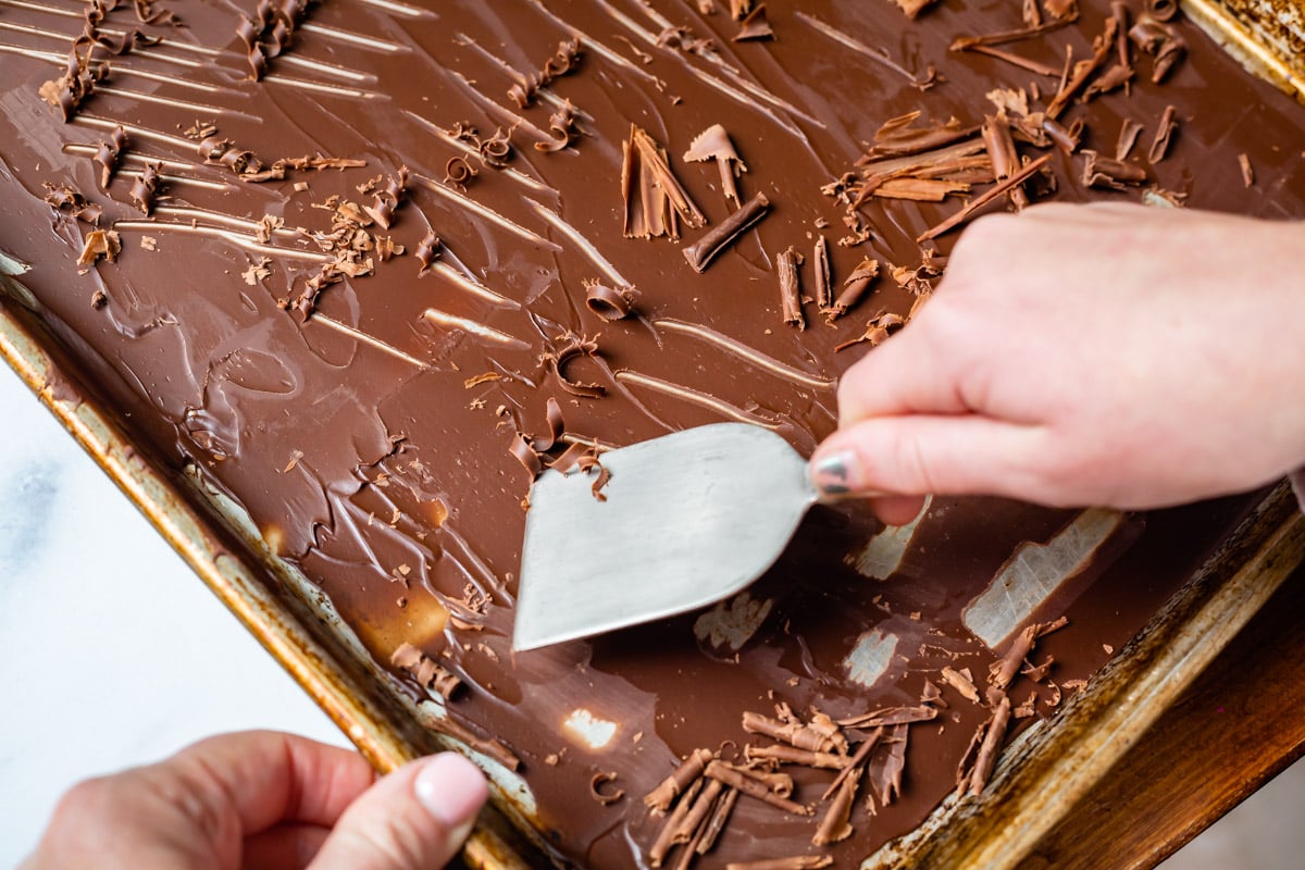 scraping chocolate curls from a pan with a metal spatula.