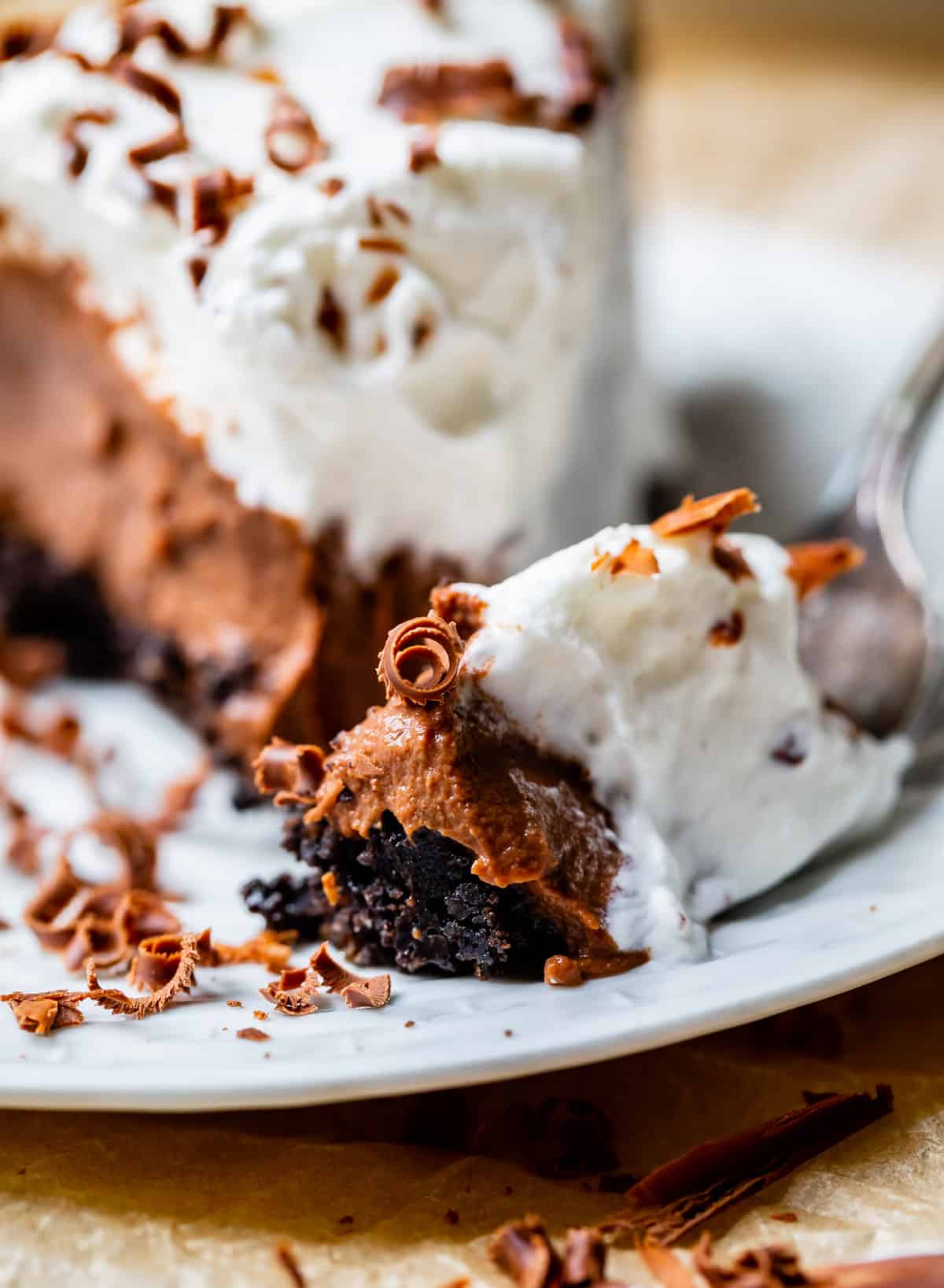 bite of chocolate cream pie with oreo crust on a white plate.
